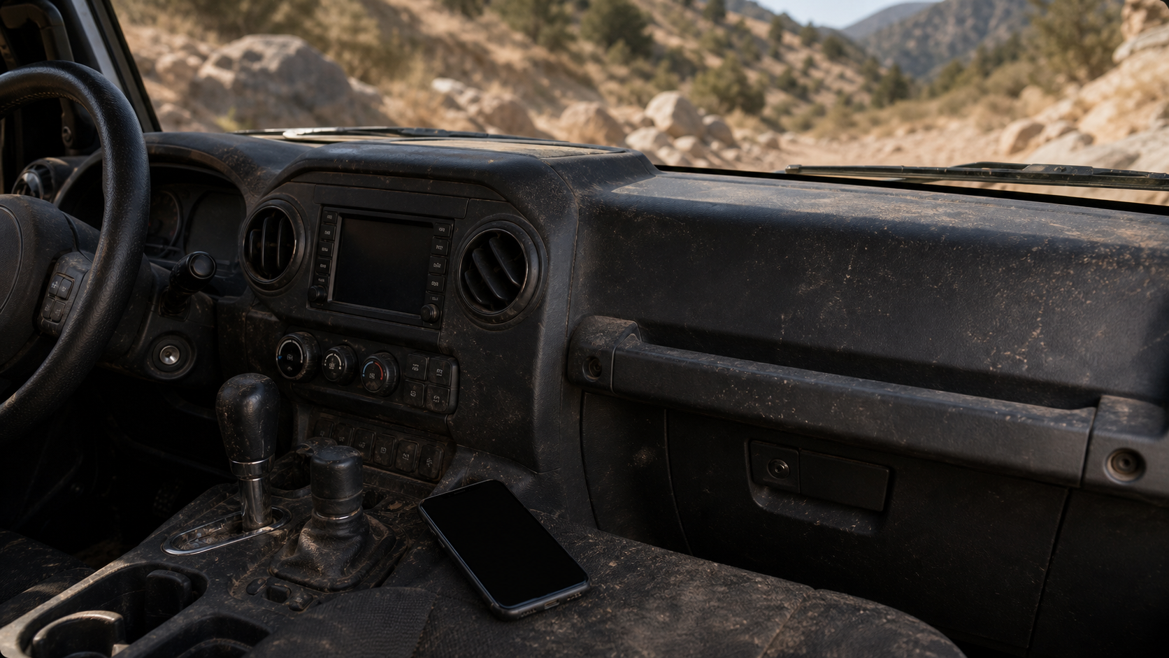 Generic off-road vehicle interior on a rocky trail with a loose phone near the console